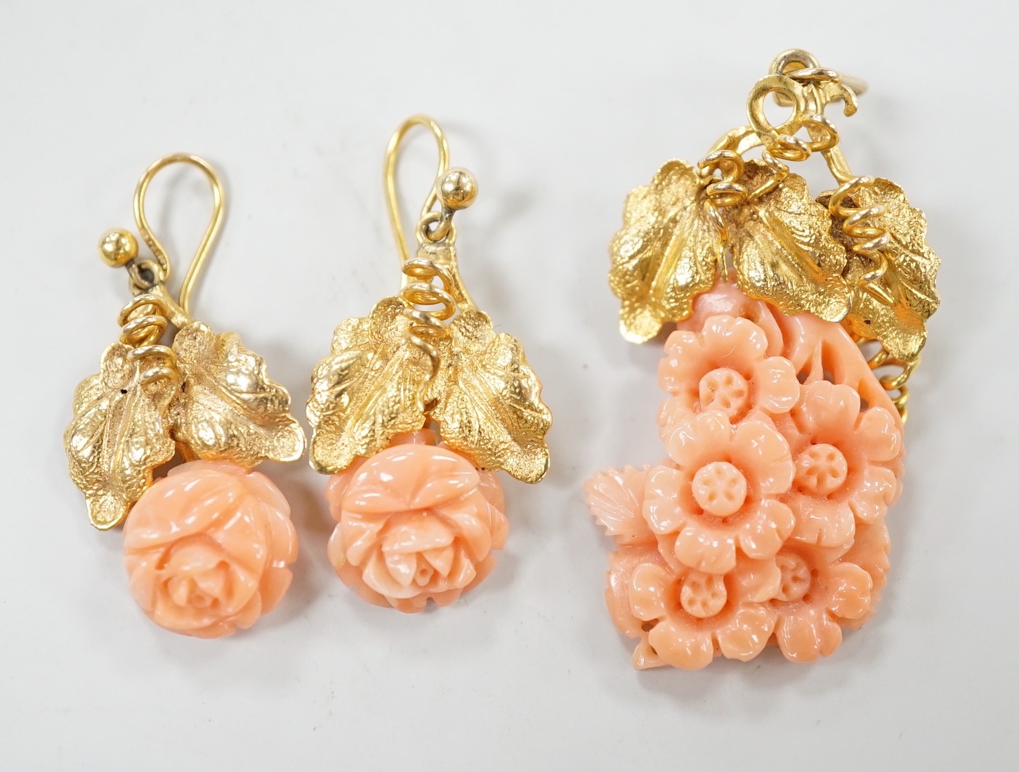 A modern suite of yellow metal and carved coral jewellery, comprising a pendant , 40mm, on chain, 45cm and a pair of matching drop earrings stamped 9ct gold, 26mm, gross 15.2 grams.